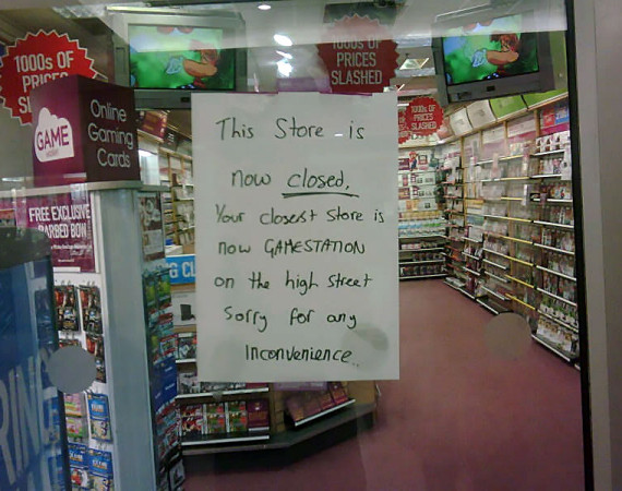 A sign on the window of a game store saying it is closed.